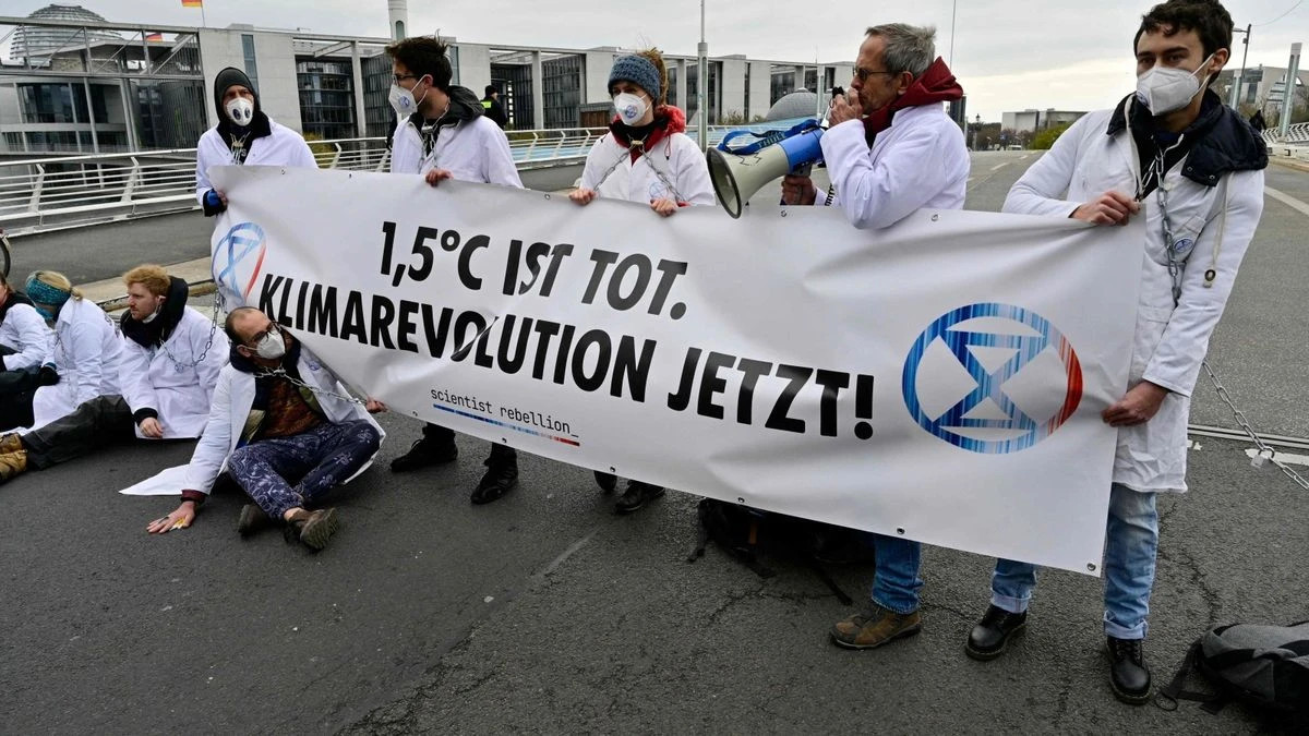 © AFP: Gruppe von Klimaschützer:innen blockiert eine Brücke in Mitte.