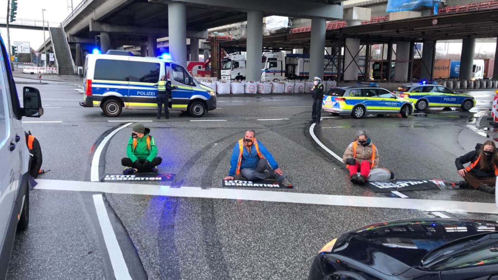 Christian Bläul (rote Hose) und weitere Aktivisten haben sich auf die Straße gesetzt und blockieren den Verkehr. Quelle: Daniel Bockwoldt